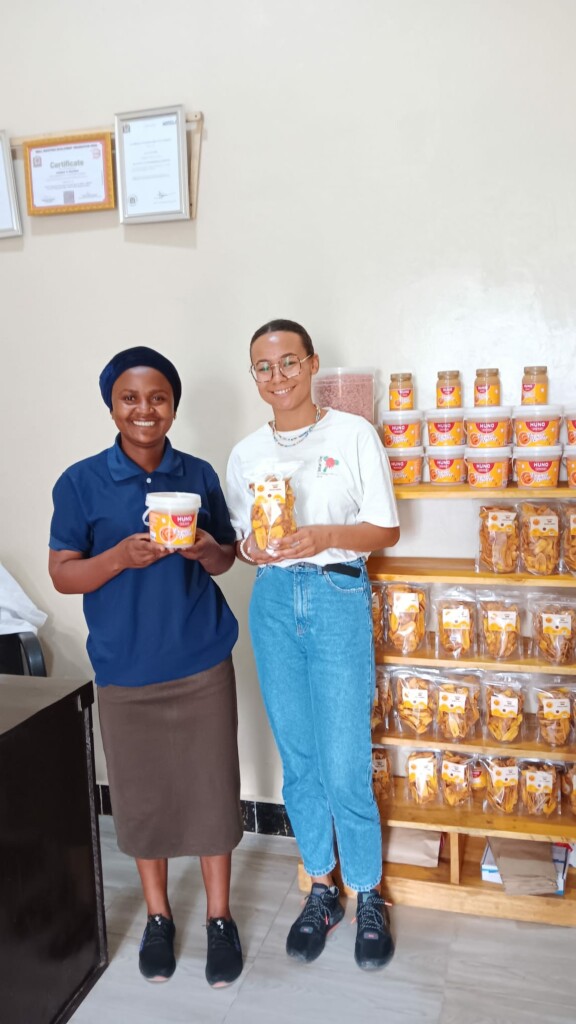 2 women pose for a picture holding jars of honey.